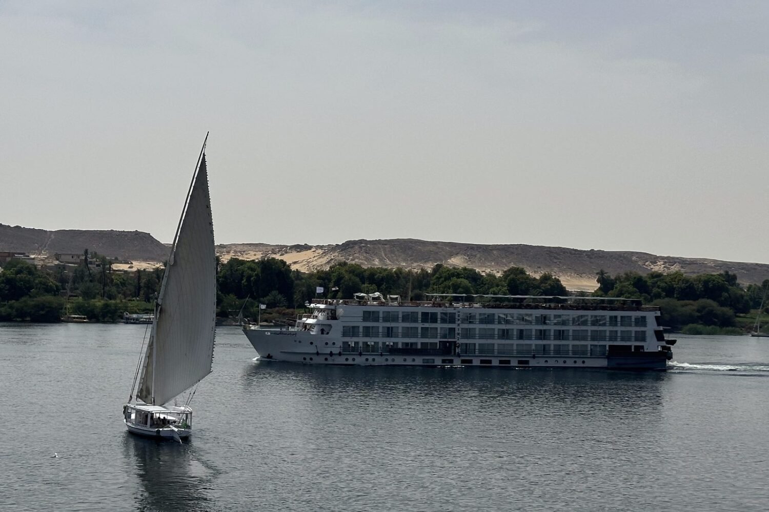 A felucca sailing past a Nile cruise ship