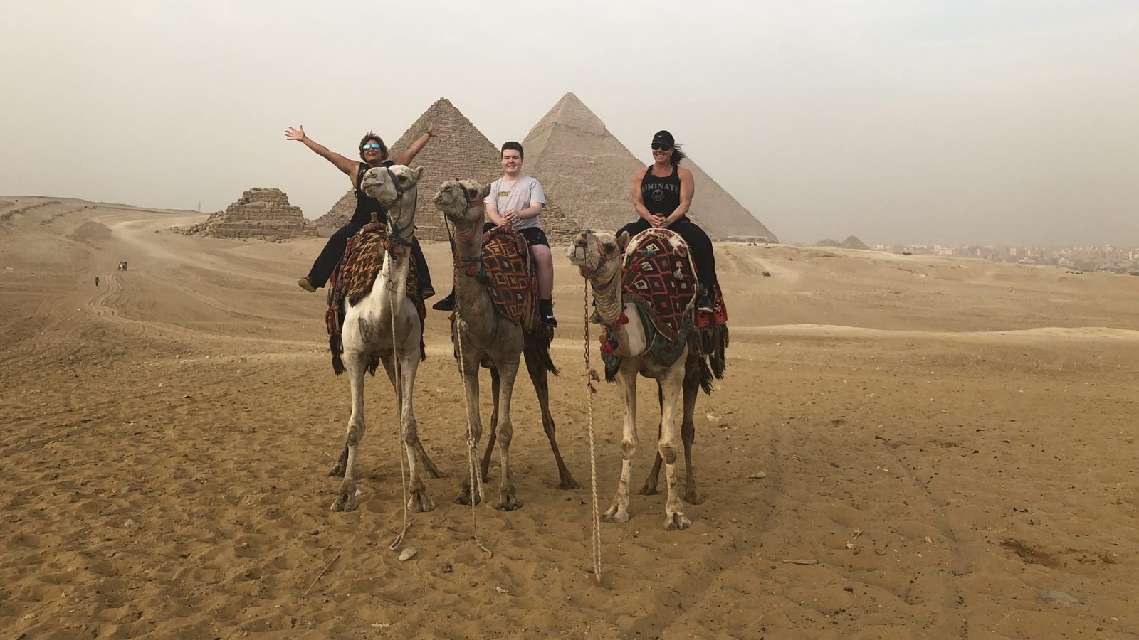 Guests on camels at the Giza pyramids Three of our guests on camels in front of the Giza pyramids, on the Cairo days of an Egypt tour with a Nile cruise