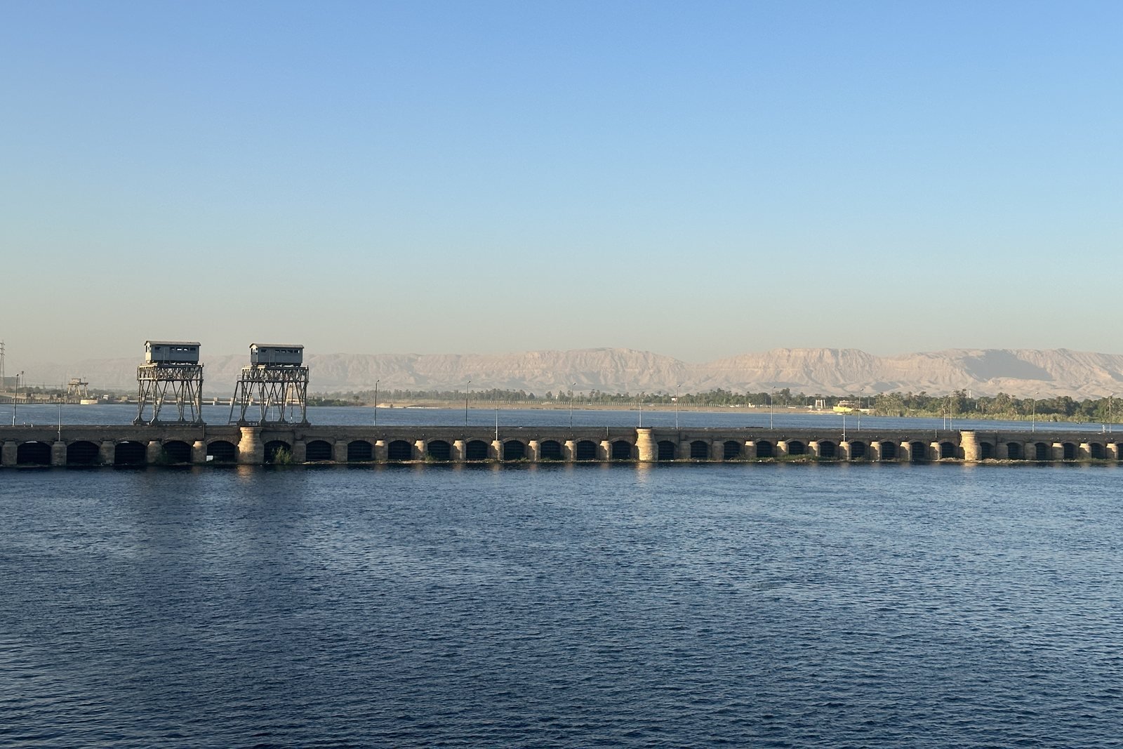 The old stone Esna barrage across the Nile, with the desert hills behind