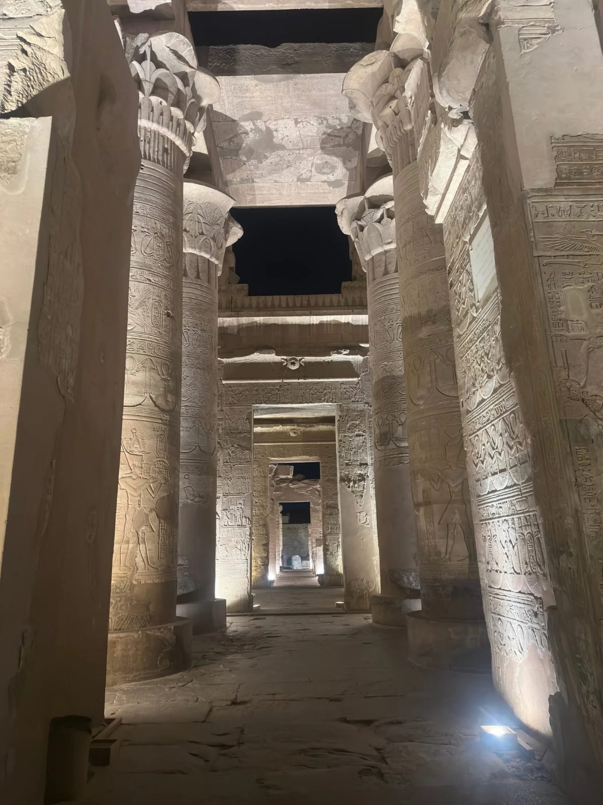 Columns of Kom Ombo temple lit at night with no visitors around